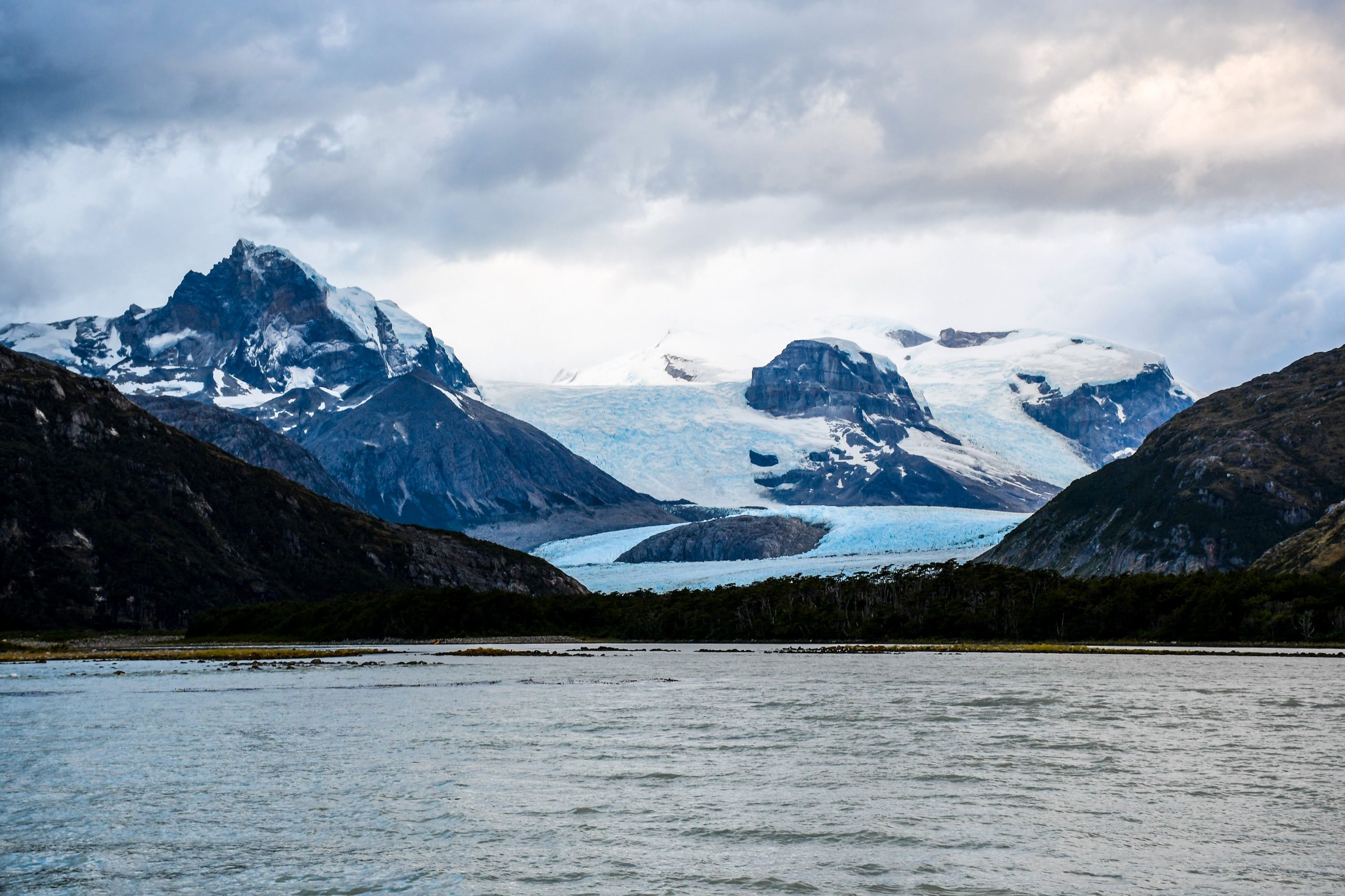 Glaciares de la Cordillera Darwin bajando hacia el canal, con las cumbres nevadas detr&aacute;s.