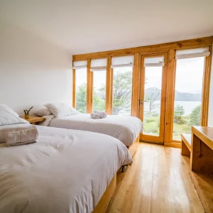 Habitación triple con dos camas y ventanal hacia el canal.