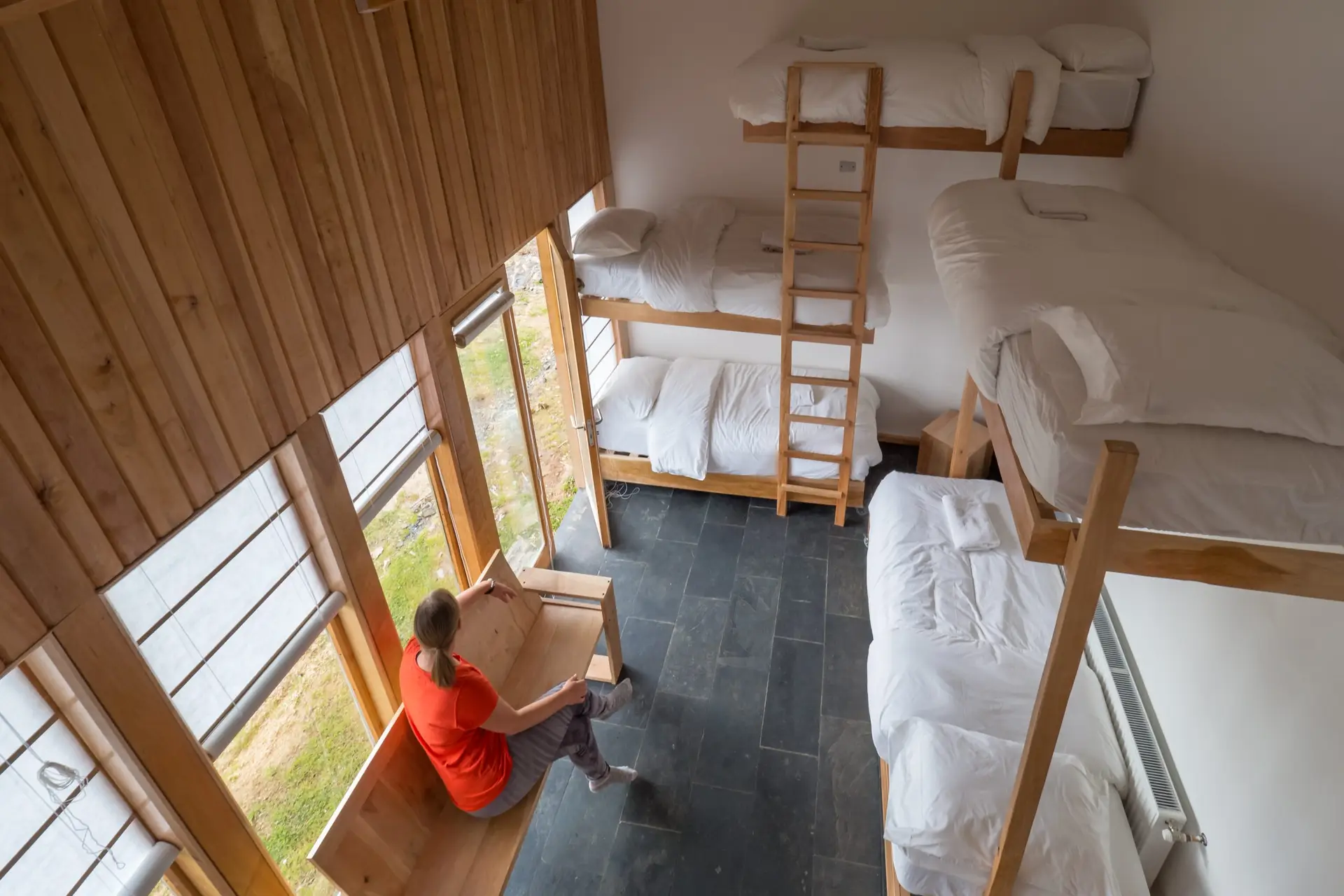 Habitaci&oacute;n grupal de Errante: camarotes de madera junto a un ventanal largo.