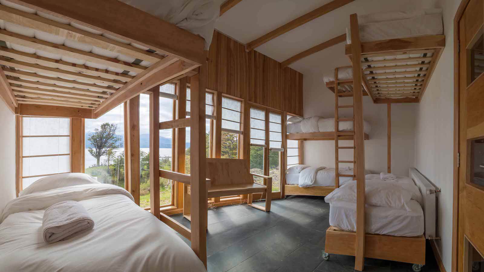 Habitación grupal con camarotes de madera y vista al canal.