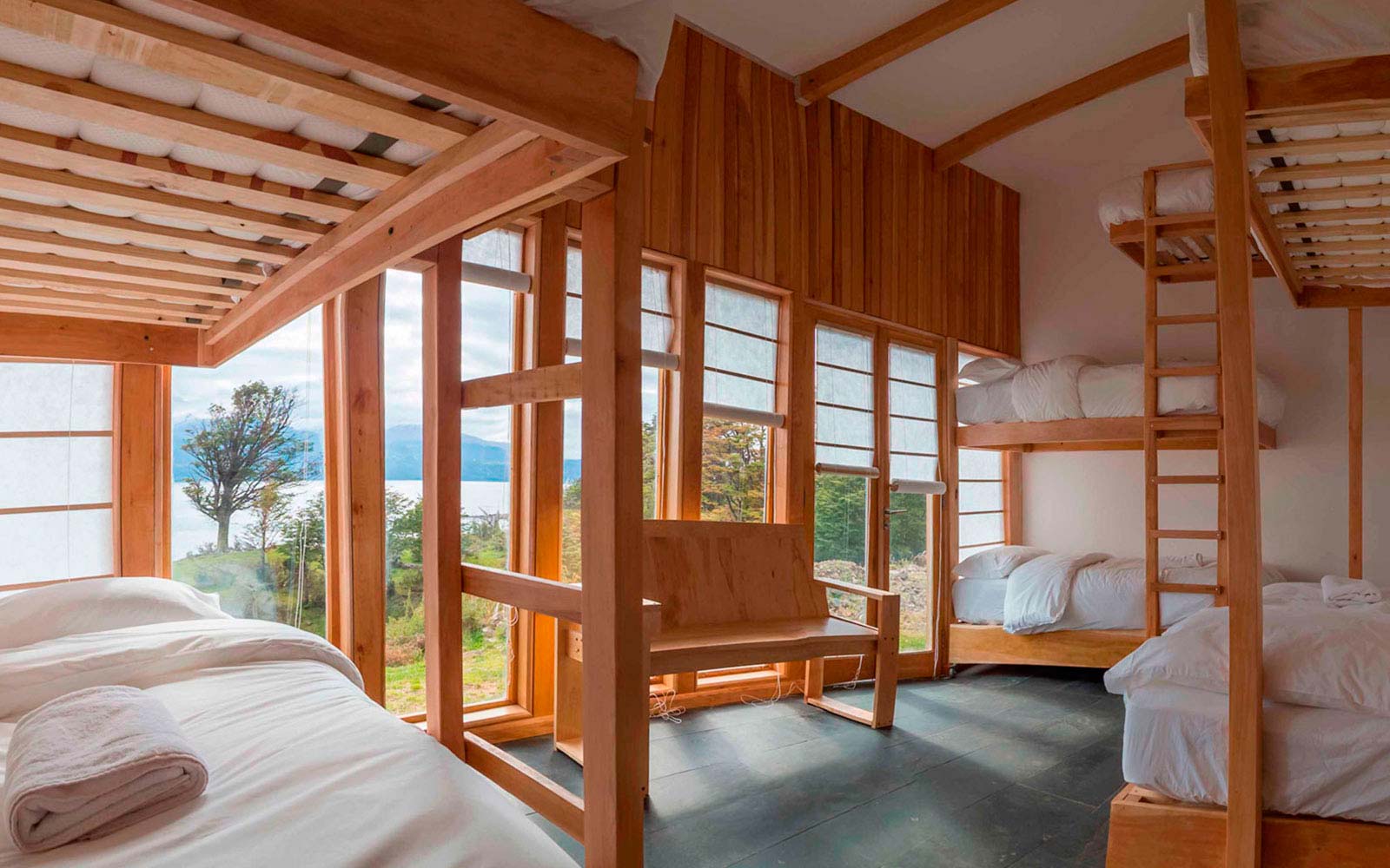 Habitación grupal con camarotes de madera de lenga y ventanales.