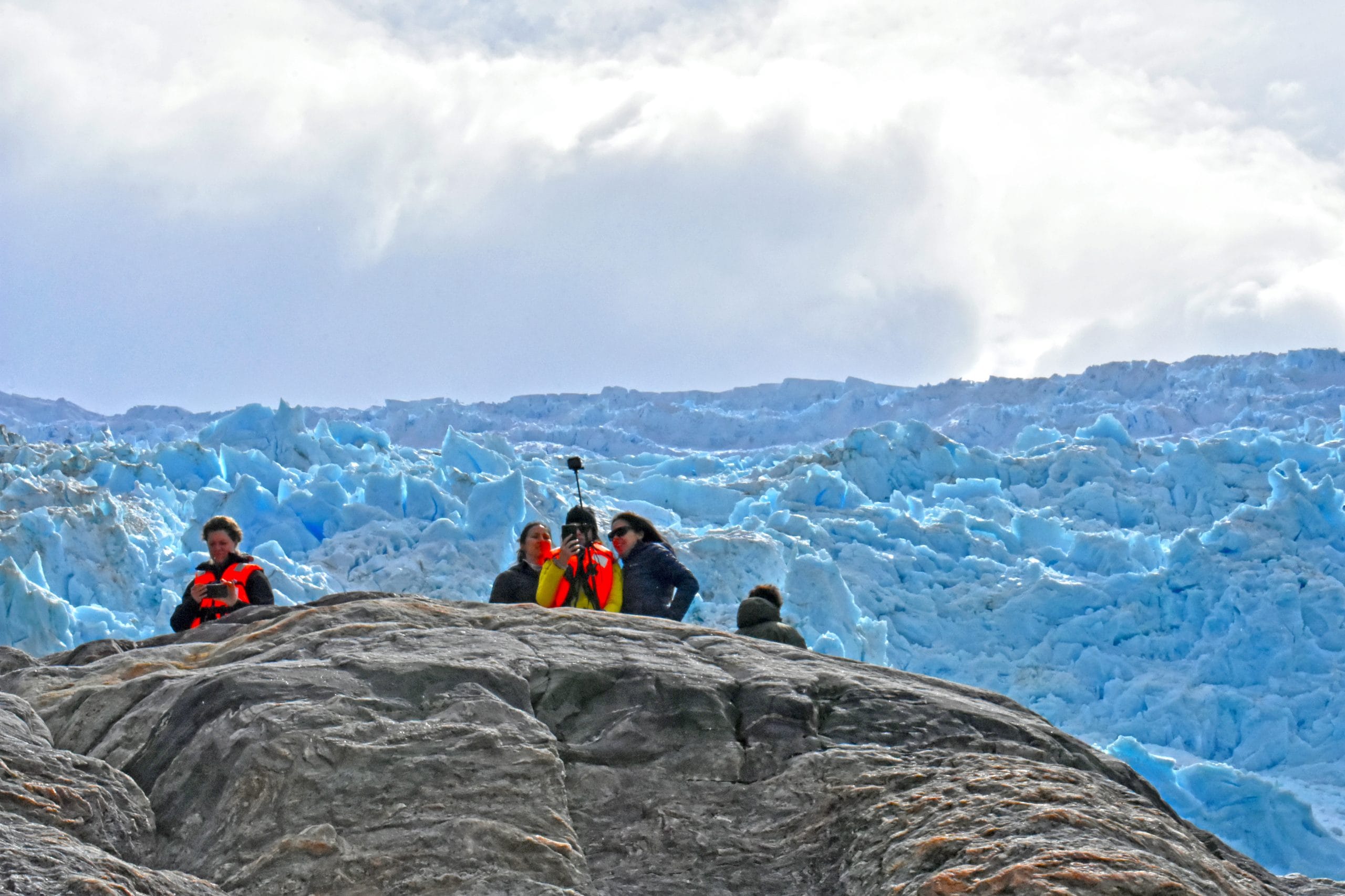Visitantes frente a la pared de hielo de un glaciar.