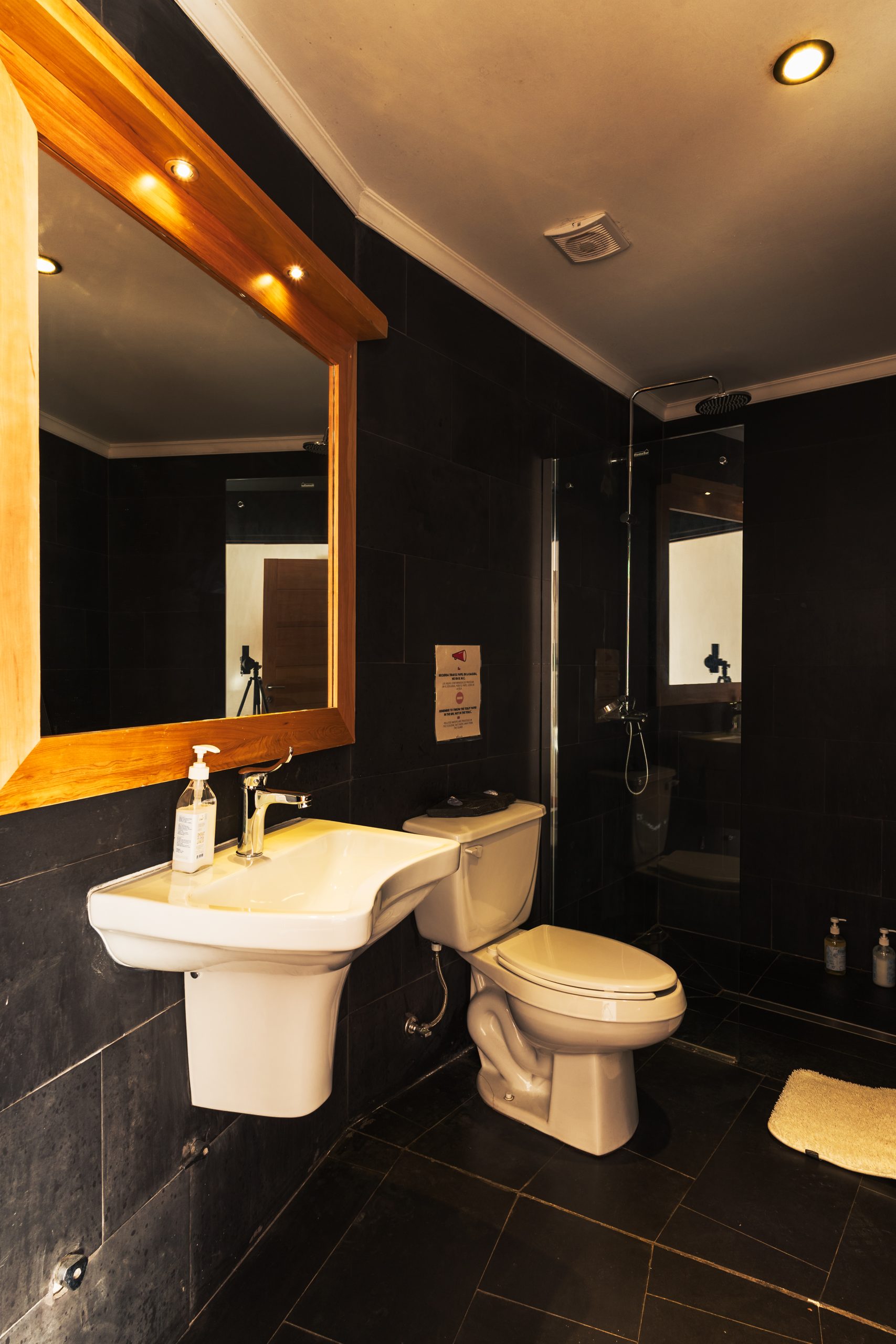 Baño de una habitación del ecolodge, con ducha y muros de piedra oscura