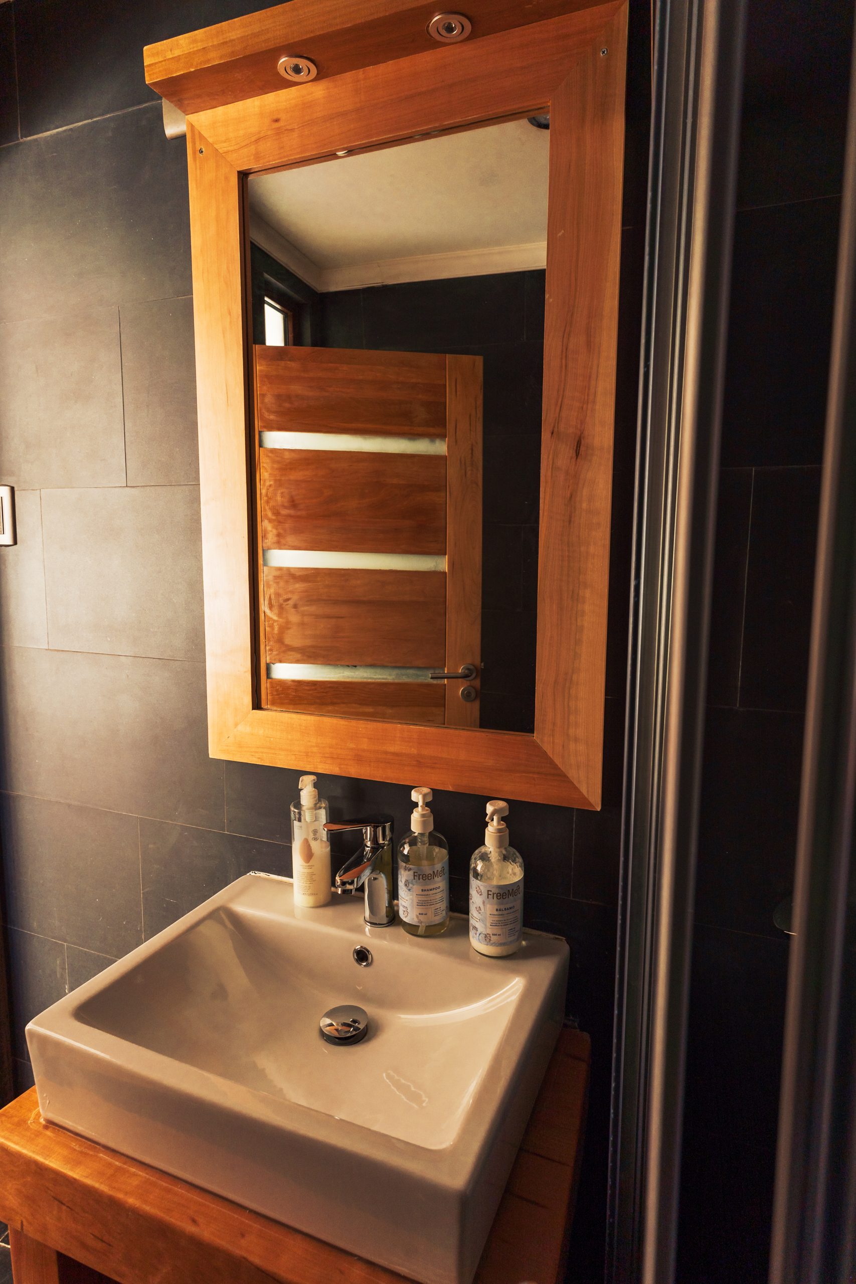 Lavamanos y espejo con marco de madera nativa en un baño del ecolodge