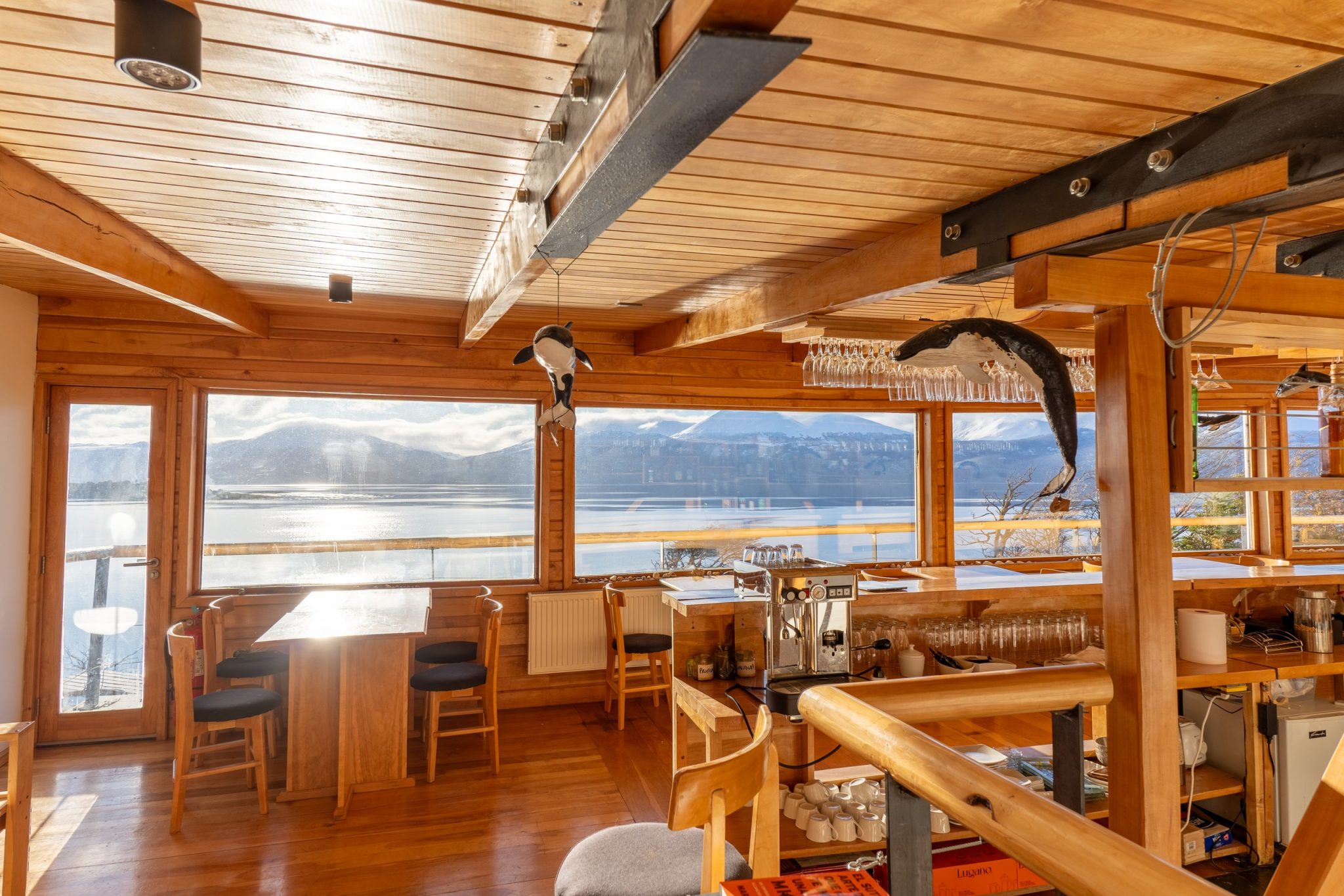 El bar del lodge, con la barra de madera, ballenas talladas colgando del techo y el canal al otro lado de los ventanales.