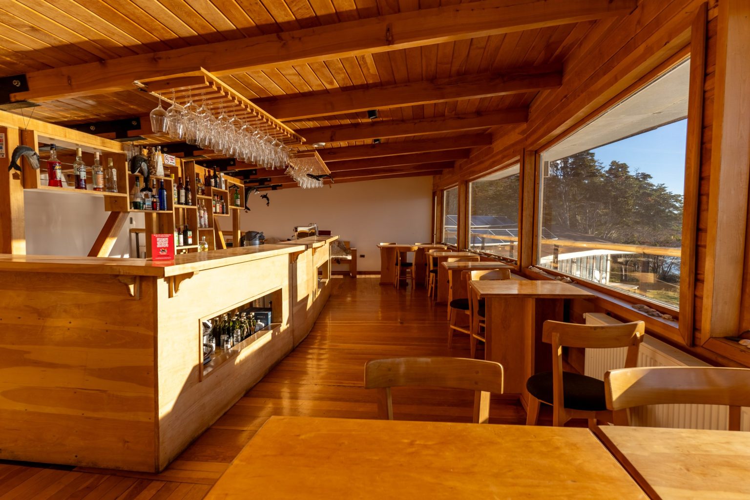 Barra de madera del bar del lodge, con ventanales hacia el bosque.