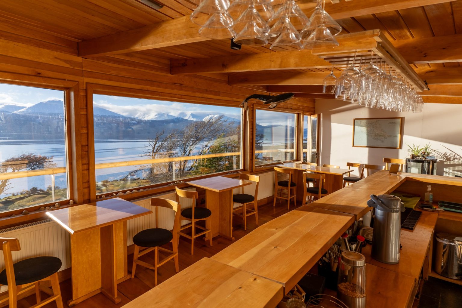 Bar y comedor de Errante con ventanales hacia el Canal Beagle y las montañas nevadas.