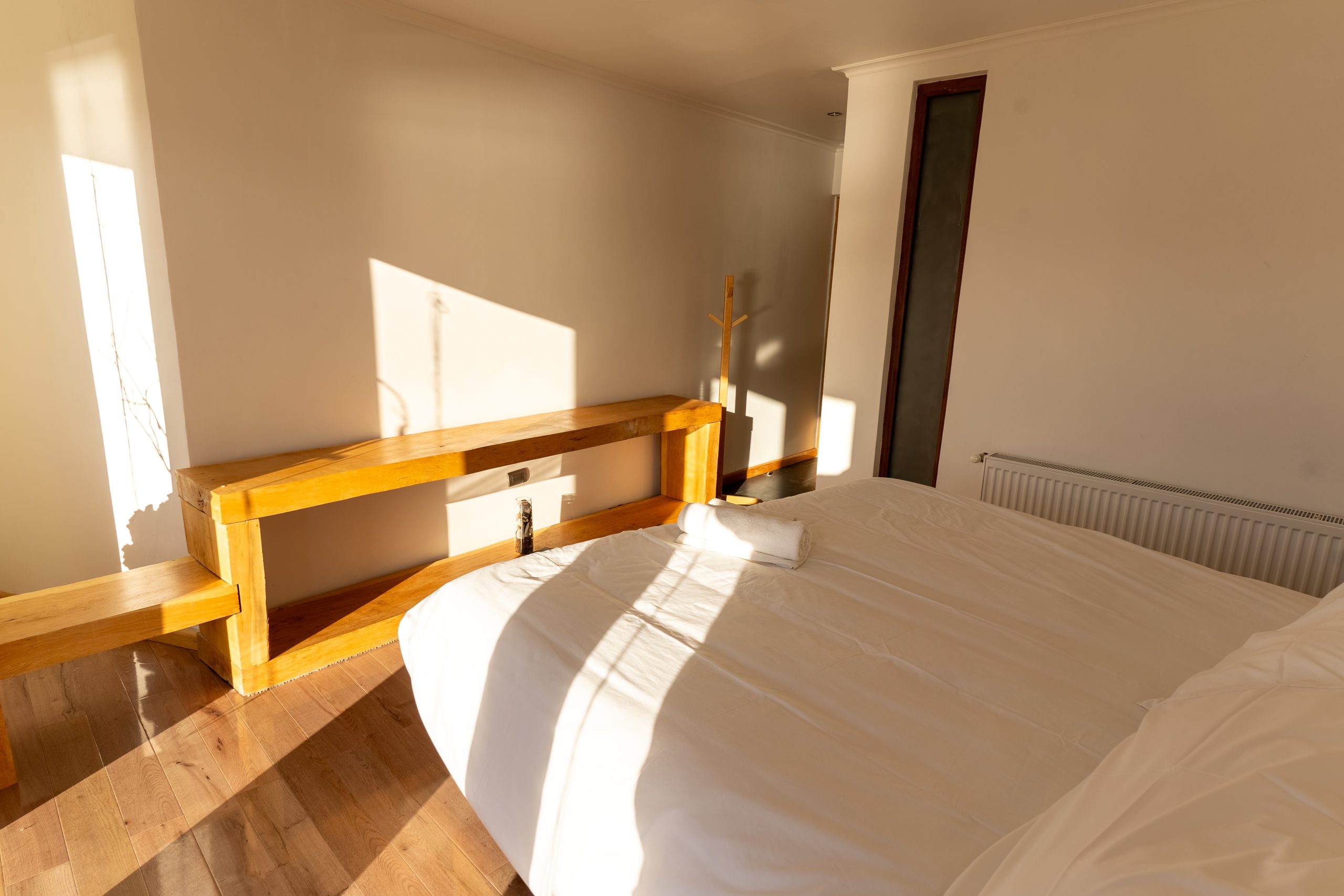 Habitación del ecolodge con cama de dos plazas y banca de madera bajo la ventana