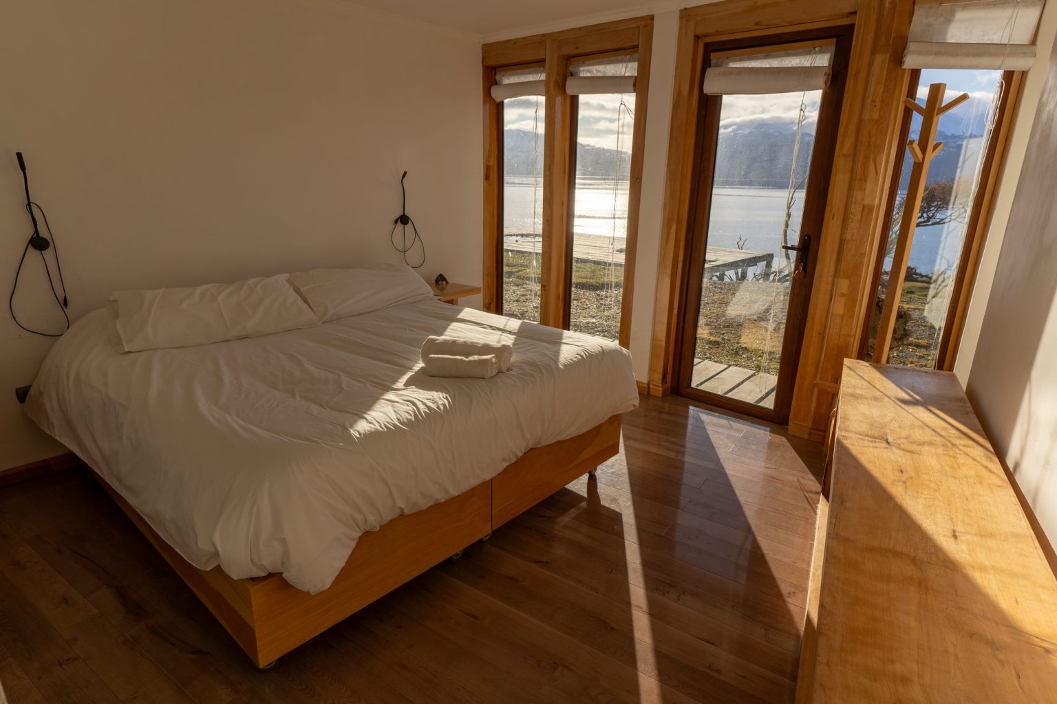 Habitación doble de Errante: cama grande y puerta abierta hacia el pasto y el canal Beagle.