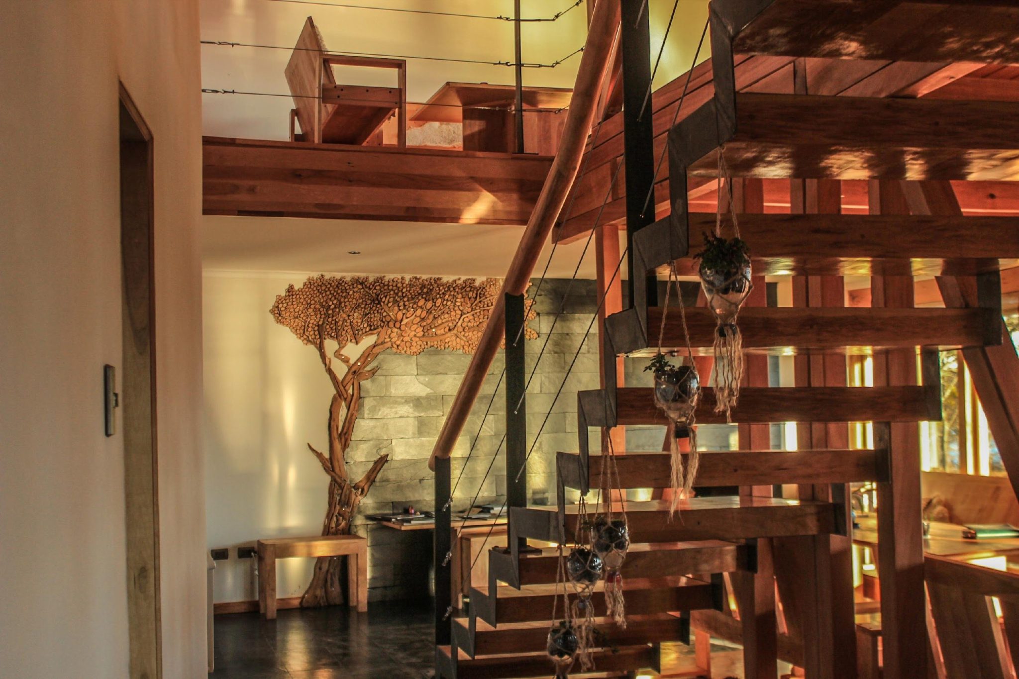 Sala de estar del lodge, con escalera de madera y ventanales.