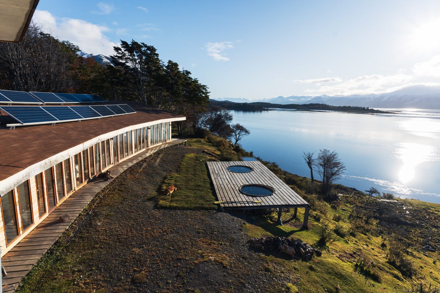 Terraza con tinajas frente a la bahía y paneles solares sobre el ecolodge